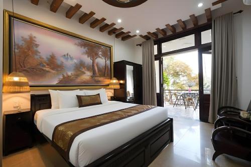 フエにあるNana Villa Hueの壁に大きな絵が飾られたベッドのある寝室