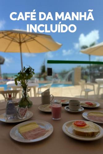 een tafel met borden eten erop met een paraplu bij Residence Vespucci in Natal