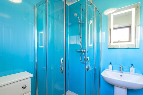 a blue bathroom with a sink and a shower at Birch Lodge 15 in Newton Stewart