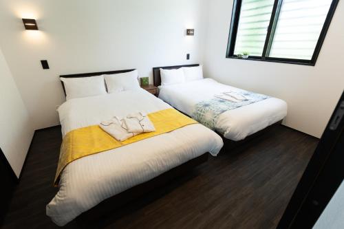 due letti in una stanza con pareti bianche di 2025年12月オープンのリベルテ瀬底サウナプールで整う1棟貸 a Sesoko