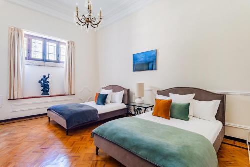 ein Schlafzimmer mit zwei Betten und einer Couch und einem Kronleuchter in der Unterkunft Estoril Royal Atlantic Villa with Ocean View in Estoril