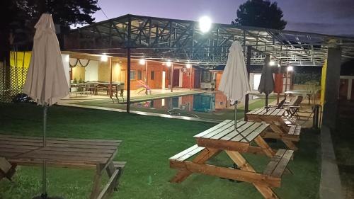 um grupo de mesas de piquenique e guarda-chuvas num quintal em Hospedaje Centro Huequén em Angol