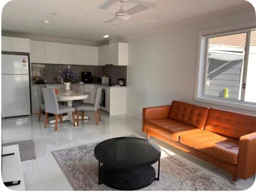 a living room with a couch and a table and a kitchen at Modern 1 or 2-Bedroom Granny Flat Near Parramatta CBD in Sydney