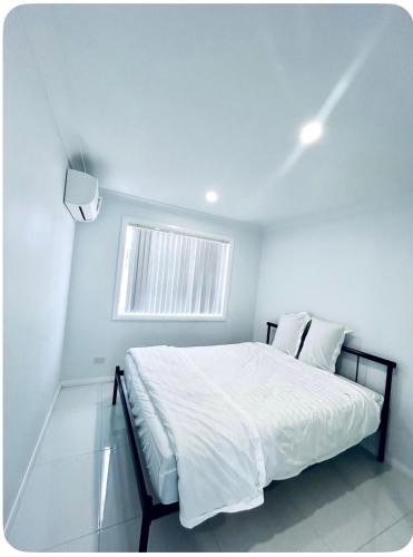 a white bedroom with a bed and a window at Modern 1 or 2-Bedroom Granny Flat Near Parramatta CBD in Sydney