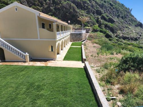 a house on the side of a hill with green grass at Corfu valley view in Paleokastritsa