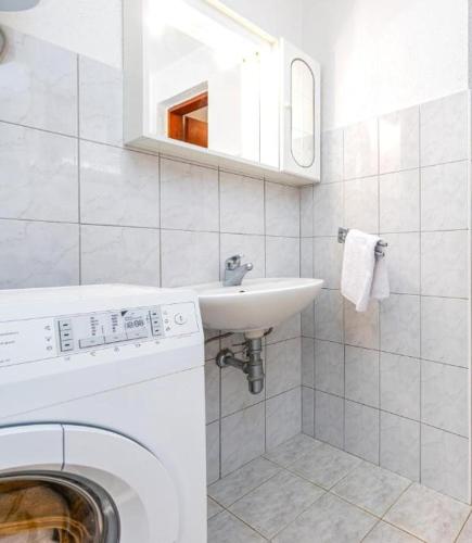 a bathroom with a washing machine and a sink at Guesthouse Diva Grabovčeva in Perušić