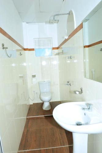 a white bathroom with a toilet and a sink at Hotel Glee in Trincomalee