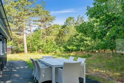a white table and chairs on a patio with a field at Beach House Near Sejerø Bay in Hønsinge