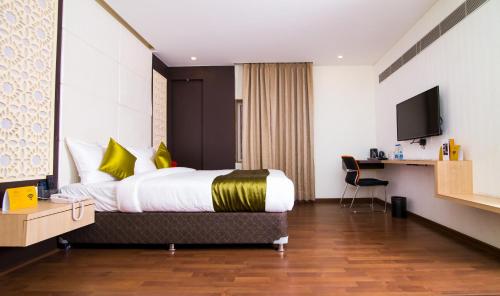 una habitación de hotel con una cama y un televisor en The Onyx Hotel, en Jamshedpur