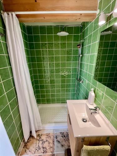 ein grün gefliestes Badezimmer mit Waschbecken und Dusche in der Unterkunft Mar Dentro in Âncora