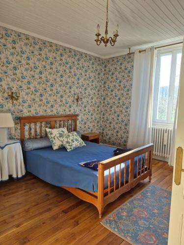 a bedroom with a bed with blue sheets and wallpaper at Au Moulin de Gary in Saint-Laurent-les-Tours