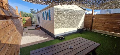 a small house with a bench in a yard at Bungalow entre oliviers et pins, -10mn de la plage in Châteauneuf-lès-Martigues