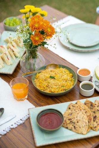 een tafel met een bord eten en een vaas met bloemen bij Jobner Haus Jaipur in Jaipur