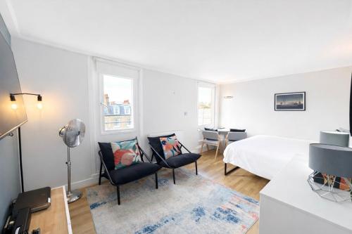 - une chambre blanche avec un lit et deux chaises dans l'établissement Camden Serviced Apartments by Globe Apartments, à Londres