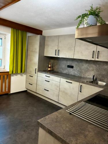 a kitchen with white cabinets and a green curtain at Ferienwohnung Lechner in Karres