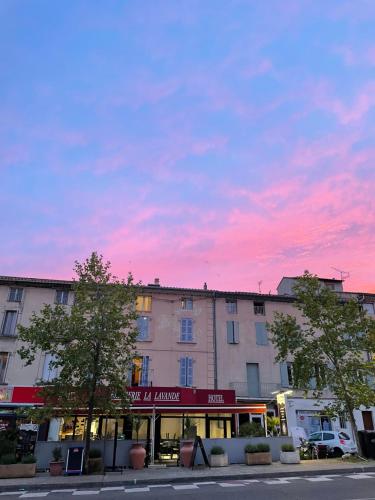a building with a pink sunset in the sky at Hôtel La Lavande in Carpentras