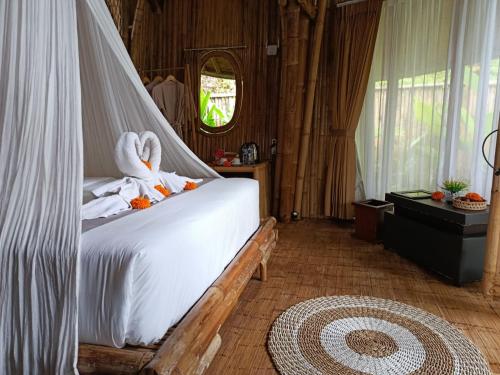 a bedroom with a bed with two swans on it at Hidden Bamboo Village in Selat