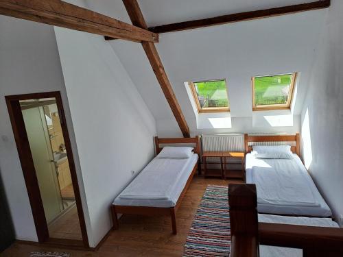 due letti in una stanza con due finestre di Pensiunea Rose a Păuleni-Ciuc