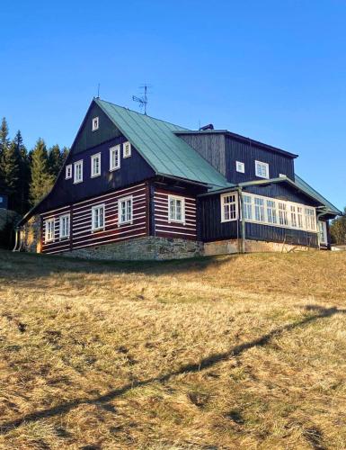 a large wooden barn sitting in a field at Horská chalupa Rychnovská bouda u skiareálu in Horní Malá Úpa