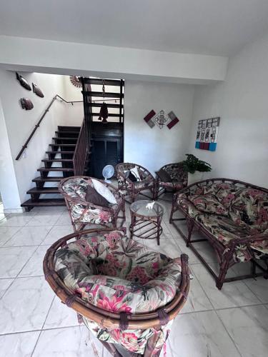 a living room with couches and chairs and a staircase at Casa espaçosa 100m da praia in Ubatuba