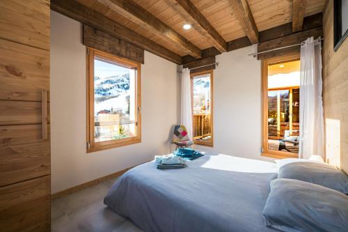 ein Schlafzimmer mit einem Bett und zwei Fenstern in der Unterkunft Chalet Saint Sorlin in Saint-Sorlin-dʼArves