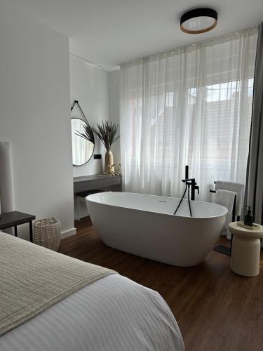 a white bath tub in a bedroom with a bed at Centar Residence in Slavonski Brod