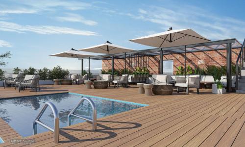 eine Terrasse mit Stühlen und Sonnenschirmen sowie einem Pool in der Unterkunft voco Amritsar by IHG in Amritsar