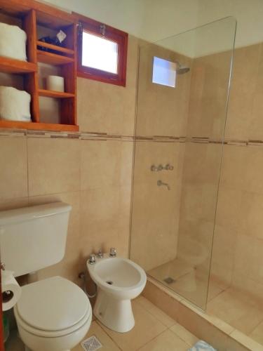 a bathroom with a toilet and a glass shower at Amaru Apart in Cafayate