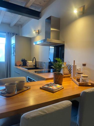 une cuisine avec une table en bois avec des chaises et un comptoir dans l'établissement Petite maison au centre de Mirepoix, à Mirepoix