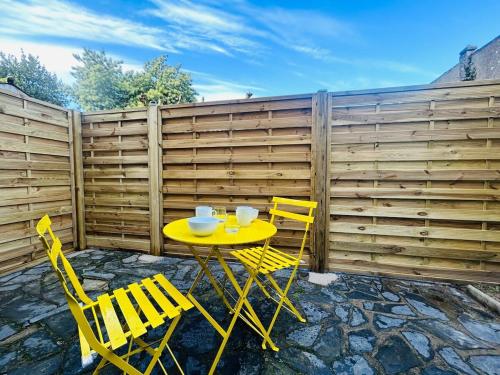 ein gelber Tisch und Stühle vor einem Zaun in der Unterkunft Casa Nature in Les Ponts-de-Cé