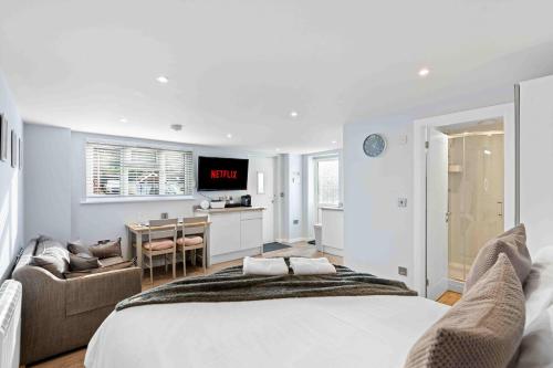 a white bedroom with a bed and a desk and a kitchen at The Patch with free parking By My Getaways in Brighton & Hove