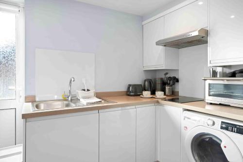 a white kitchen with a washing machine and a sink at The Patch with free parking By My Getaways in Brighton & Hove
