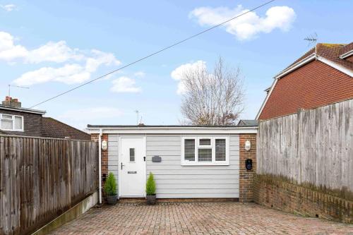 a garage with a white door and a fence at The Patch with free parking By My Getaways in Brighton & Hove