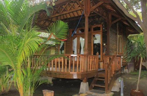 a wooden gazebo in a garden with palm trees at Bronze Bungalow in Gili Meno