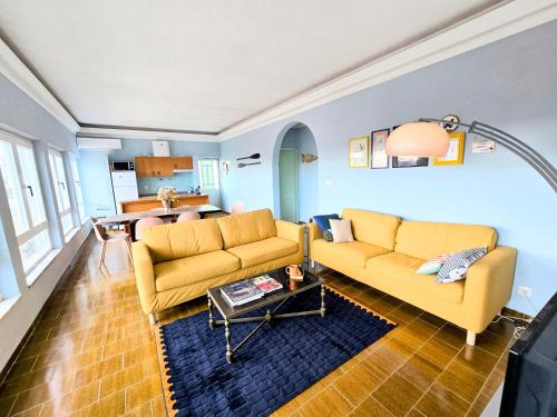 a living room with two yellow couches and a table at Casa Bonito in Vila Nova De Cacela