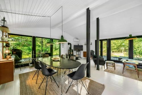 a dining room and living room with a table and chairs at Summer House In Houstrup With Scenic Views in Nørre Nebel