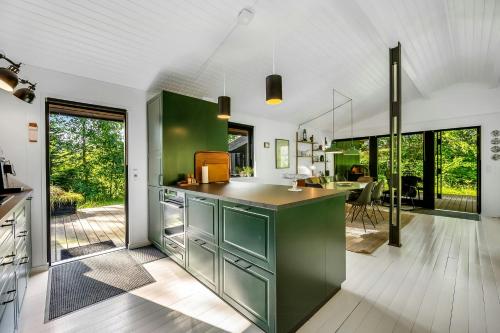 a kitchen with green cabinets and a dining room at Summer House In Houstrup With Scenic Views in Nørre Nebel