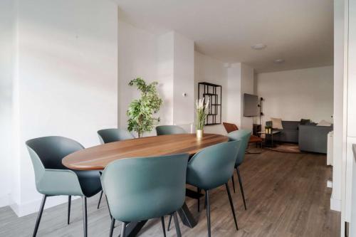 a dining room with a wooden table and blue chairs at Modern 2BR Apartment near Rotterdam Central Station in Rotterdam