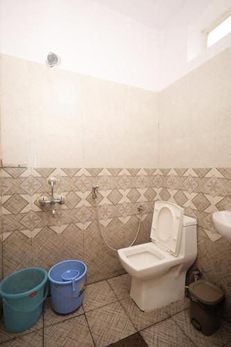 y baño con aseo, lavamanos y cubos. en Srishti Homestay, en Madikeri