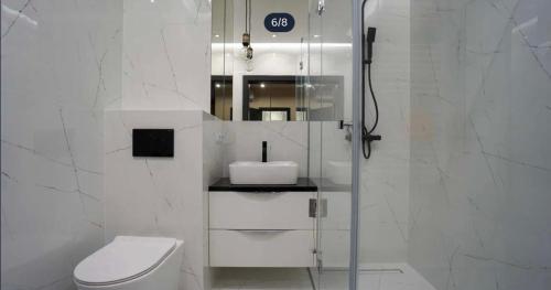 een witte badkamer met toilet en douche bij Apartament Jurowiecka 17 in Białystok