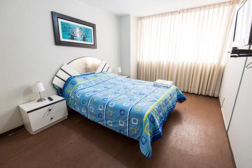 une chambre avec un lit avec une couette bleue et une fenêtre dans l'établissement Departamento Temporal Pardo, à Lima