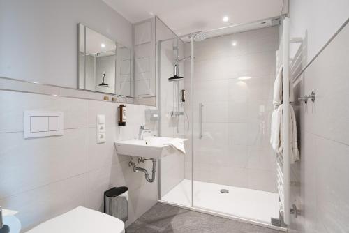 グラール・ミューリッツにあるHotel Ostseewogeのシャワーと洗面台を備えた白いバスルーム
