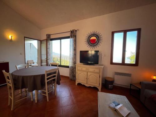 ein Wohnzimmer mit Tisch und Fernseher in der Unterkunft Gîtes la fontaine corse vue panoramique in Loreto-di-Casinca