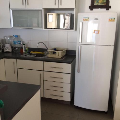 a kitchen with a white refrigerator and a sink at Dpto de playa en Paracas in Paracas