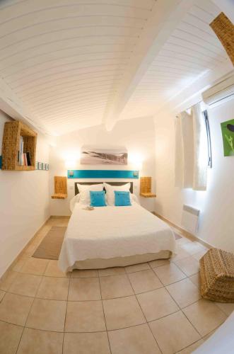 une chambre avec un grand lit blanc avec des oreillers bleus dans l'établissement L'Oliveraie de Paul, à Aigues-Mortes