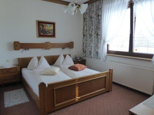 a bedroom with a bed with white sheets and a window at Pension Leyrer in Kötschach