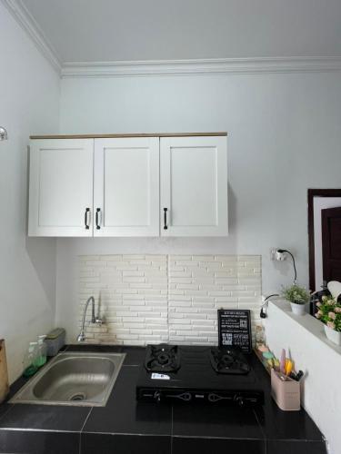 une cuisine avec une cuisinière et un évier et des armoires blanches dans l'établissement Casa de Brisa BnB, à Prampuan