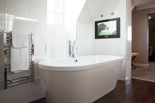 海斯廷斯的住宿－班納坦溫泉酒店，带浴缸的白色浴室以及墙上的电视。