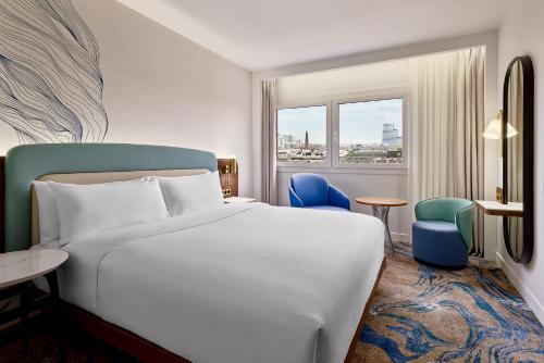 パリにあるLe Méridien Paris Arc De Triompheのベッドと椅子と窓のあるホテルの部屋
