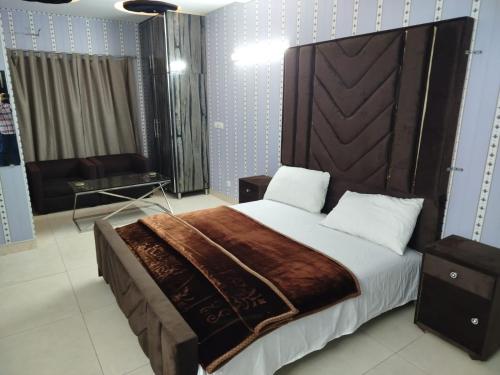 ein Schlafzimmer mit einem großen Bett mit einem hölzernen Kopfteil in der Unterkunft Grand Orchard One Hotel in Lahore